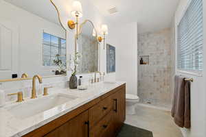 Bathroom featuring double vanity, a walk in shower, and light tile patterned flooring