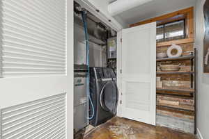 Laundry area featuring concrete flooring, washer / dryer, and water heater