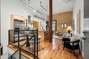 Living area featuring a high ceiling, brick wall, rail lighting, and light wood-type flooring
