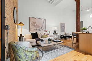 Living room featuring light wood finished floors, a high ceiling, and track lighting