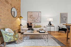 Living area with brick wall and hardwood / wood-style flooring