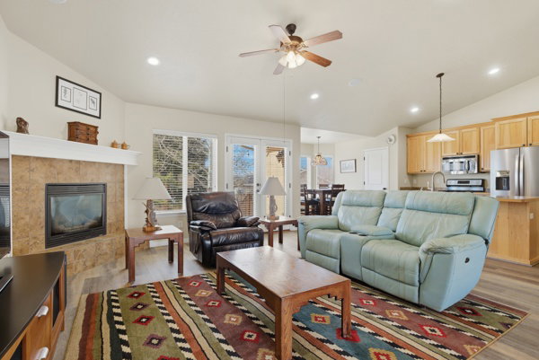 Living room featuring vaulted ceiling, a fireplace, recessed lighting, ceiling fan, and light wood-style floors