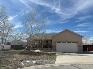 Single story home featuring stucco siding, an attached garage, concrete driveway, and a covered porch