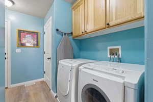 Laundry area with independent washer and dryer, LVP floors, and cabinet space and storage closet