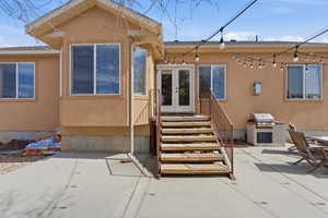 Rear view of house with french doors, stucco siding, and a patio area. Stairs of custom cut local stone.