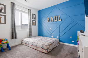 Bedroom featuring an accent wall and carpet floors