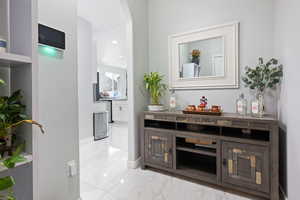 Bar featuring light marble finish flooring, recessed lighting, and arched walkways