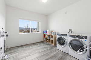 Laundry area with wood finish floors and washing machine and clothes dryer