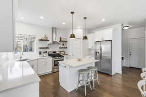 Kitchen with stainless steel appliances, open shelves, white cabinetry, a center island, and pendant lighting