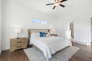 Bedroom with dark wood finished floors, lofted ceiling, ceiling fan, and ensuite bathroom