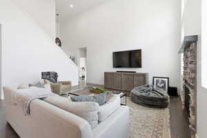 Living area featuring wood-type flooring, a high ceiling, and a stone fireplace