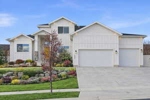 Modern inspired farmhouse with board and batten siding, an attached garage, concrete driveway, and a front yard