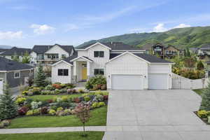 View of front facade featuring a residential view, board and batten siding, an attached garage, a gate, and driveway