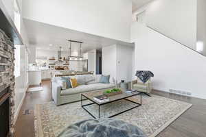 Living area featuring dark wood finished floors, a fireplace, a high ceiling, and recessed lighting