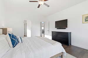 Bedroom with dark wood-style floors, a ceiling fan, and lofted ceiling