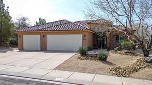 Mediterranean / spanish house with an attached garage, concrete driveway, and stucco siding