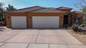 View of front of property with stucco siding, an attached garage, concrete driveway, and a tiled roof