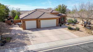 View of front facade featuring an attached garage, stucco siding, concrete driveway, and a gate
