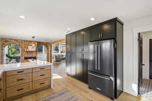 Kitchen featuring freestanding refrigerator, light wood-style floors, a fireplace, pendant lighting, and open floor plan