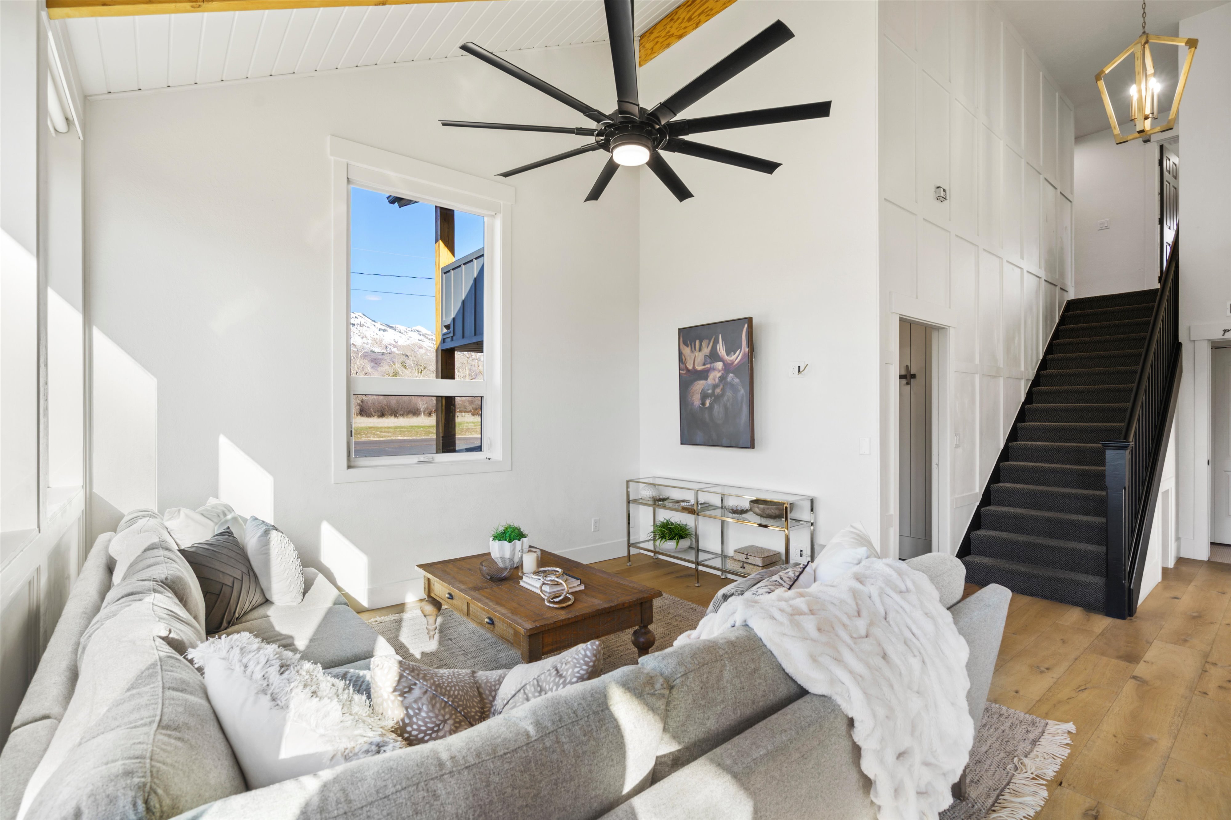 Living area with light wood finished floors, a ceiling fan, lofted ceiling, and suspended lighting