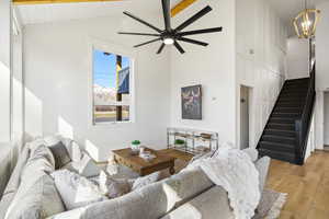 Living area with light wood finished floors, a ceiling fan, lofted ceiling, and suspended lighting
