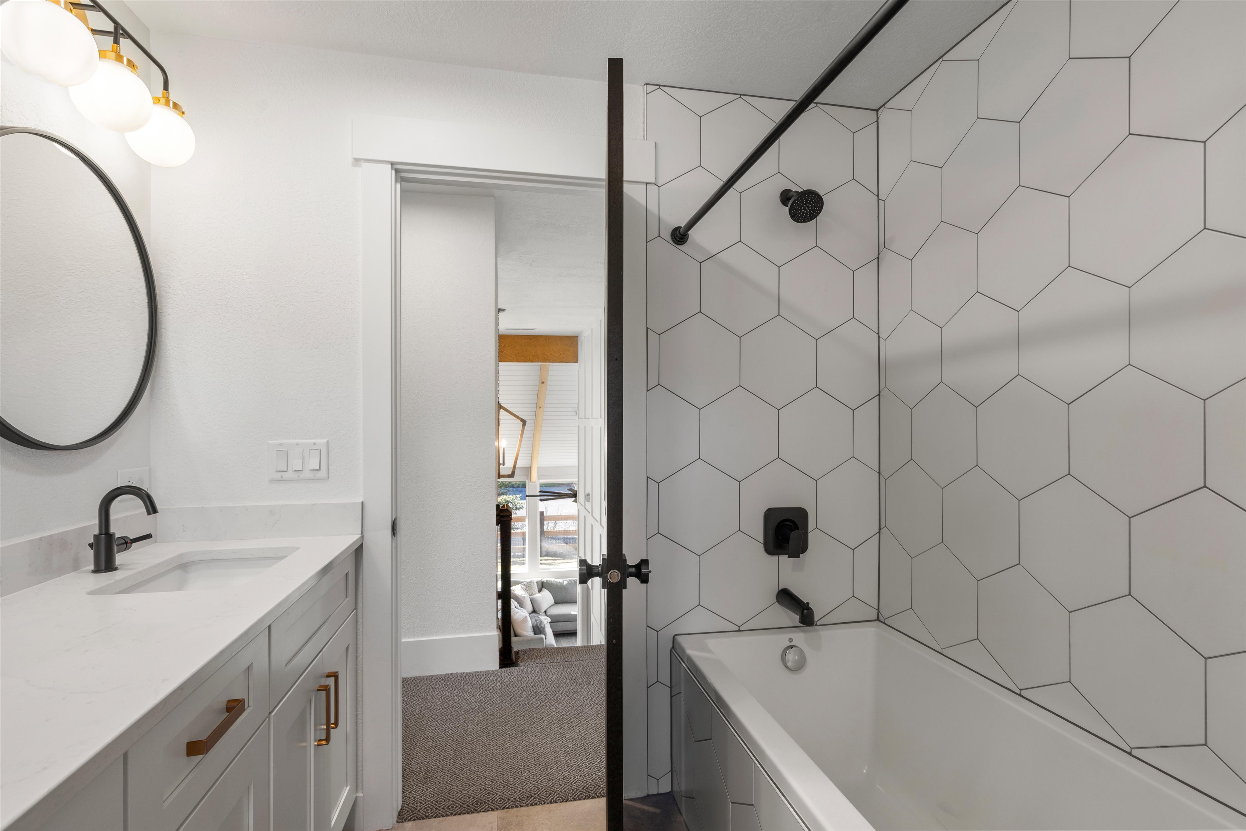 Bathroom with vanity, washtub / shower combination, and light colored carpet