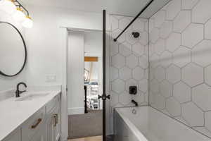 Bathroom with vanity, washtub / shower combination, and light colored carpet