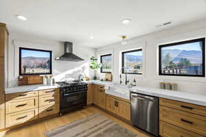 Kitchen featuring high end range, dishwasher, light wood-style flooring, a mountain view, and recessed lighting