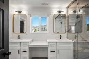 Full bath featuring double vanity, a marble finish shower, and a mountain view