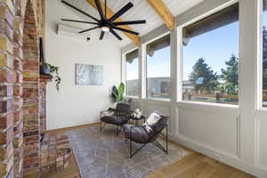 Sunroom with vaulted ceiling with beams, wood finished floors, and a wall mounted mini split