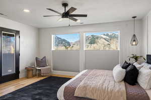 Bedroom with a mountain view, light wood-style floors, access to exterior, a ceiling fan, and a textured ceiling