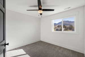 Carpeted spare room with a mountain view and a ceiling fan
