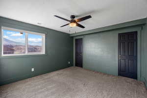 Unfurnished bedroom featuring a textured wall, carpet flooring, ceiling fan, a closet, and a mountain view