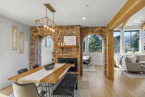 Dining area with a brick fireplace, light wood-style floors, and a chandelier