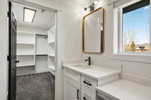 Bathroom with vanity, dark colored carpet, and a walk in closet
