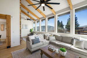 Sunroom / solarium with hardwood / wood-style floors and a high wooden beamed ceiling