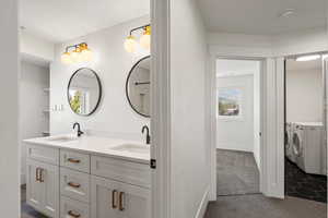 Full bathroom featuring double vanity, independent washer and dryer, and dark carpet