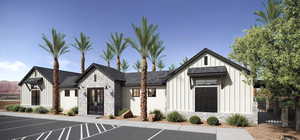 View of front facade featuring stone siding, board and batten siding, french doors, and uncovered parking