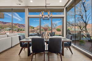 Sunroom with a mountain view, suspended lighting, and wood-type flooring