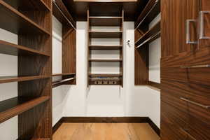 Walk in closet with light wood finished floors