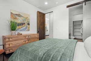 Bedroom with a barn door, connected bathroom, and recessed lighting