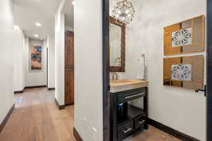 Bathroom with light wood-type flooring, suspended lighting, and vanity
