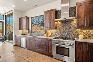 Kitchen featuring stainless steel appliances, tasteful backsplash, dark wood finish cabinetry, light wood-type flooring, and recessed lighting