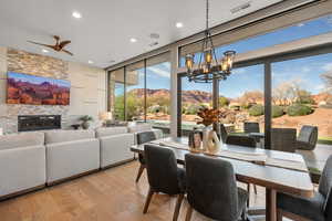 Dining room featuring a mountain view, light wood-style flooring, a fireplace, suspended lighting, and floor to ceiling windows