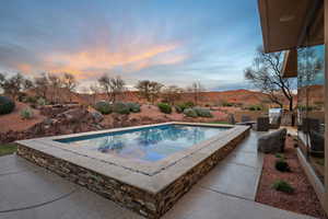 Pool at dusk featuring area for grilling, a patio, and an outdoor pool