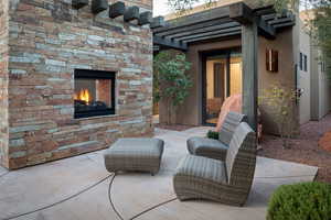 View of patio / terrace featuring an outdoor stone fireplace and a pergola