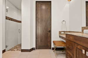 Full bath with vanity, a stall shower, and light tile patterned floors