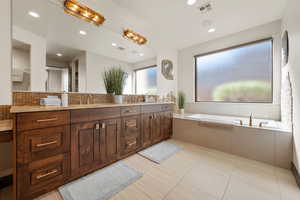 Full bathroom featuring a bath, double vanity, decorative backsplash, recessed lighting, and light tile patterned floors