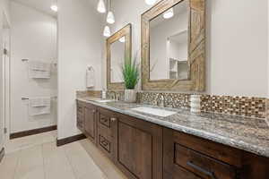 Bathroom featuring double vanity, light tile patterned flooring, and tasteful backsplash