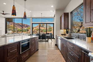 Kitchen with dark wood finish cabinetry, a mountain view, light stone counters, light wood-style flooring, and stainless steel microwave